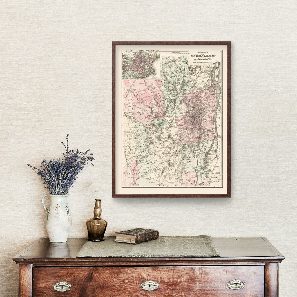 Framed Adirondacks vintage map on a wall above a wooden dresser with decorative items.