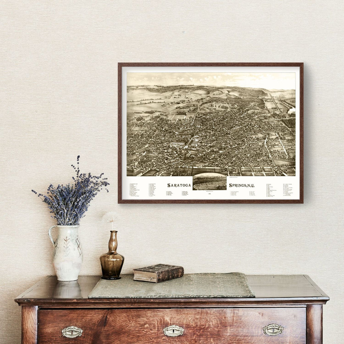 Framed vintage-style map of Saratoga Springs on a wall above a wooden dresser with decorative items.