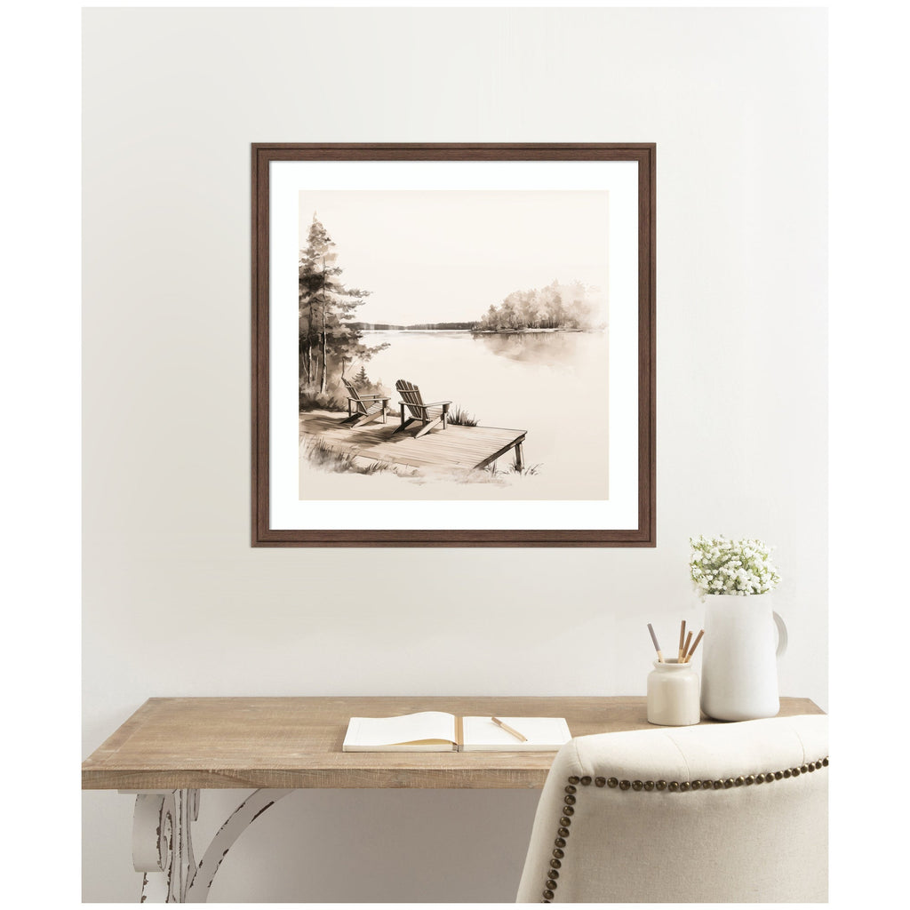 Framed artwork of a lakeside scene on a wall above a wooden desk.