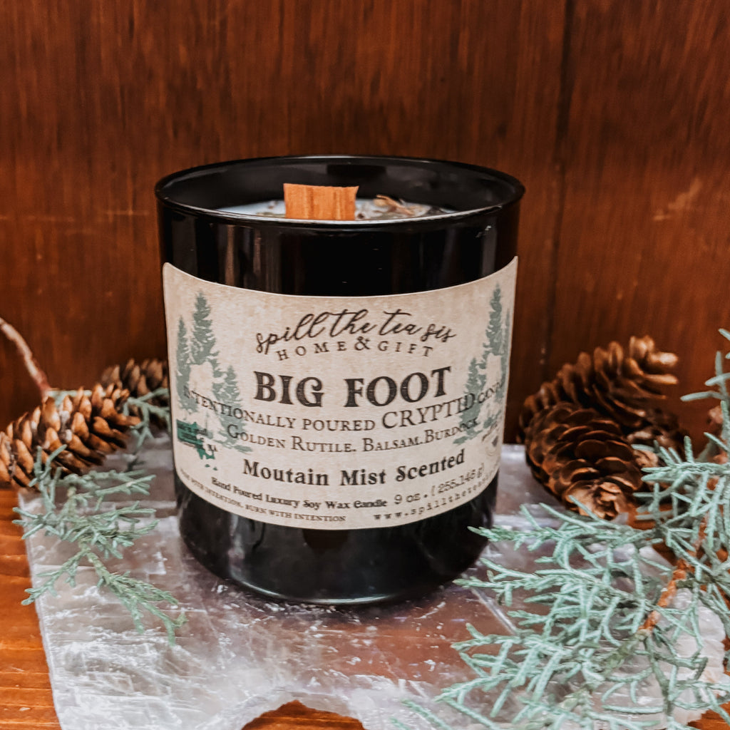 Bigfoot Sasquatch Candle with a label on a wooden surface with decorative elements