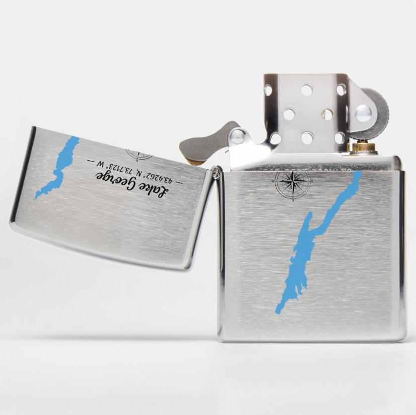 A brushed silver metal lighter shown open, with a blue map outline of New York State on both the lid and body, plus black script text on the inside of the lid.